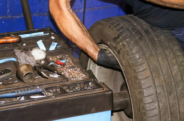 Manos de un mecánico trabajando arreglando un pinchazo en una rueda.