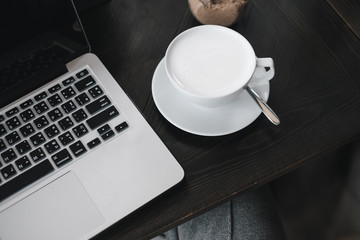 laptop and white milk cup on wood table. View from above