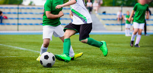Running Football Soccer Players. Sports Competition Between Youth Soccer Teams. Young Boys in Hard Duel Playing Soccer Game. Junior Footballer Kicking Soccer Ball - obrazy, fototapety, plakaty