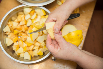 Quince fruit peeled with hands on a light background with space for an inscription . Woman peels quince .