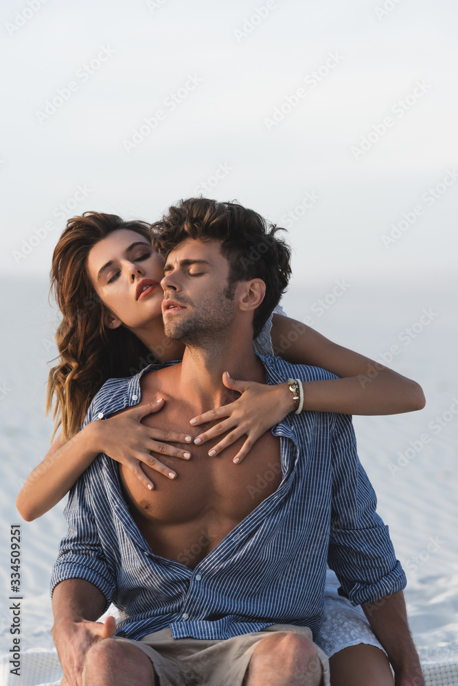 Wall mural passionate young woman touching boyfriend torso on beach