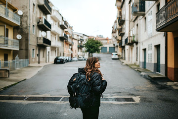 young woman with backpack in the middle of the street of an old town ready for adventures