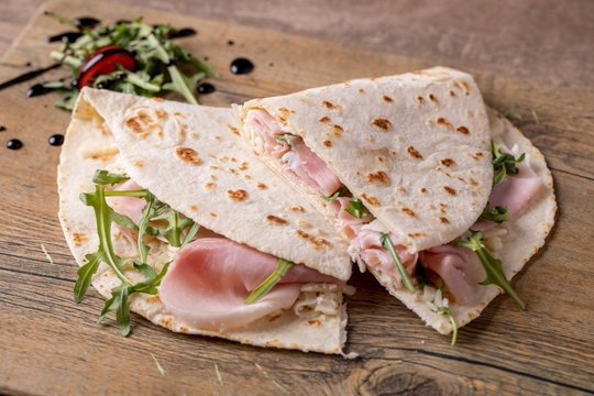 details of tasty italian piadina with ham and arugula