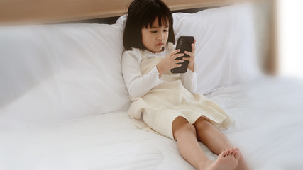 Girls playing on phones in bed, social problems causing children to lack development.