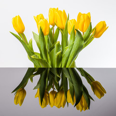 Bukiet żółtych tulipanów i lustrzane odbicie w kałuży.  Rozlana woda i odbicie kwiatów.