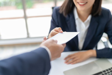 Young Asian business woman receiving salary or bonus money from boss or manager at office happily.