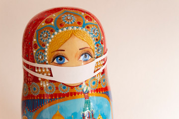 Matryoshka is crying. Wooden painted souvenir Russian toy Matryoshka in a medical mask is a concept...