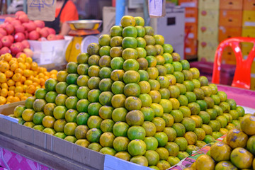 A pyramid of fresh limes and lemons in a market.