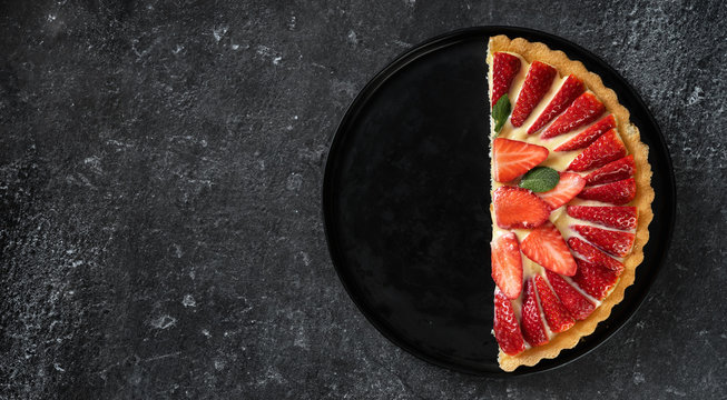 A half of fresh strawberry flan on black background