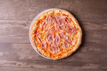 details of pizza with mozzarella and ham on a wooden background