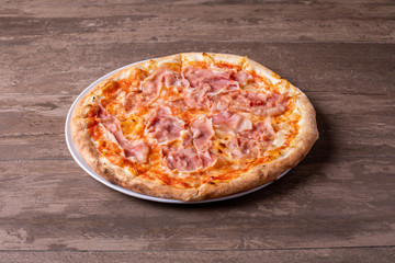details of pizza with mozzarella and ham on a wooden background