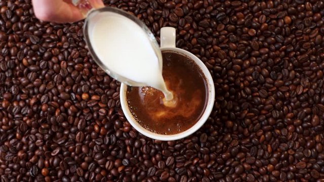 Pouring cream into a cup of coffee