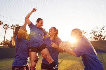 Womens Football Team Celebrating Winning Soccer Match Lifting Player Onto Shoulders - obrazy, fototapety, plakaty