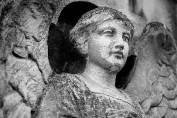 Bottom view of sad angel. Ancient stone statue. Death, pain and end of life concept.