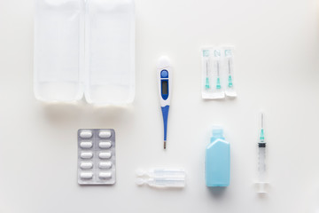 Medical supplies kit for health emergencies, consisting of thermometer, bandages, analgesics, antiseptics, serum, hand sanitizer, needles and syringe, on white background, selective focus
