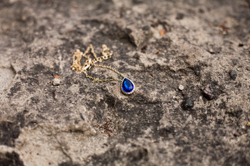 Gold pendant sapphire lie on the stone.