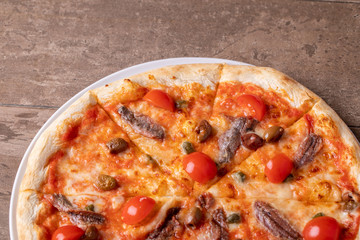 Close up of tasty hot pizza with anchovies and tomatos