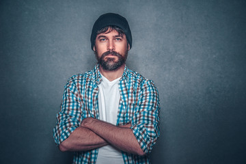 Handsome bearded man in casual clothes crossed arms with beanie on isolated background