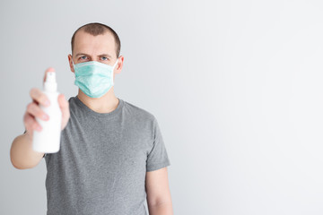 coronavirus protection and disinfection concept - man in protective mask spraying sanitizer spray and copy space over white