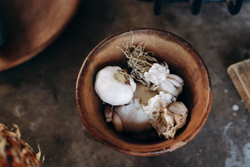 The heads of garlic lie in a ceramic plate on a concrete table
