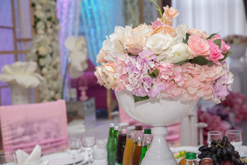 wedding table, wedding decorations . Large vase with beautiful roses stands on rich served dinner table .Wedding flower composition for guest . Beautiful pink and white flowers on table .