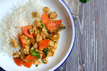 chicken and vegetable sauté with rice on a white plate