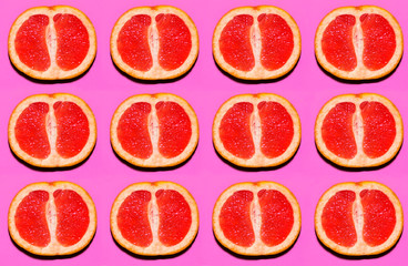 Fruit pattern. Slices of grapefruit on pink background