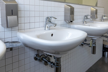 Row of white porcelain sink in public toilet. Antivirus health protection concept