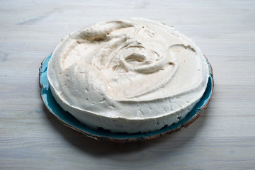 Meringue on a blue plate on a white background. Ready dessert or semi-finished product for Pavlova’s dessert.