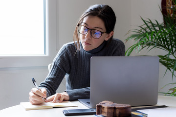 Young woman freelancer tele working and writing on her notebook