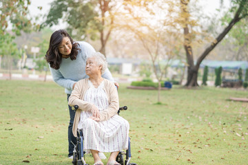 Help and care Asian senior or elderly old lady woman patient sitting on wheelchair at park in nursing hospital ward : healthy strong medical concept