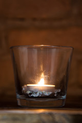 candle lit inside a glass with pine cone