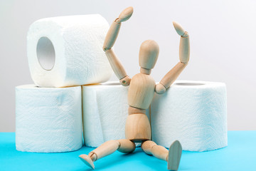 Wooden man sitting on a toilet paper rolls. Coronavirus global panic 2020.