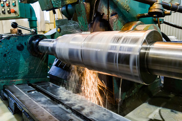 Processing and manufacturing of a shaft with an abrasive stone on a circular grinding machine, sparks are cooled by a liquid.