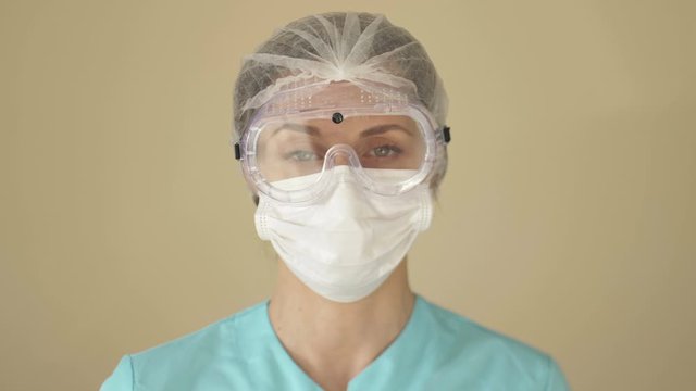 Female doctor or nurse removes a medical mask and safety glasses. Tired look.