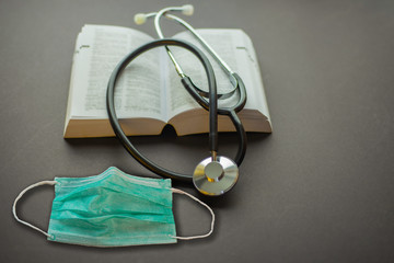 Stethoscope on a book and medical mask with back background.