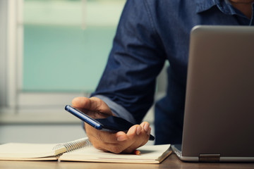 Male employee with cell phone and laptop working from home for preventing corona virus covid-19, concept of social distancing.