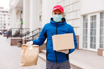 Courier in protective mask and medical gloves delivers takeaway food. Delivery service under...