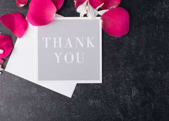 Fancy Greeting card to express thanks with posh red rrose petals from above as a background