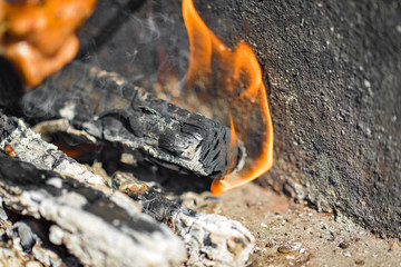 Burning log with coals and ash closeup.