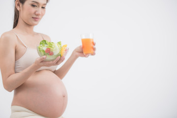 care about unborn child. pregnancy, healthy food and people concept, happy pregnant woman eating vegetable salad and drinking orange juic for breakfast at home. pregnancy and healthy organic nutrition