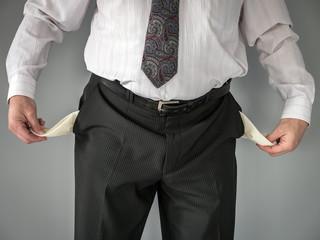 Businessman with empty pockets over gray