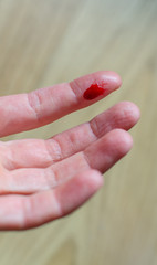 Finger with red blood drop caused by accident, knife cut...