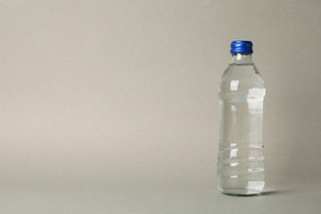 Bottle with water on gray background, space for text