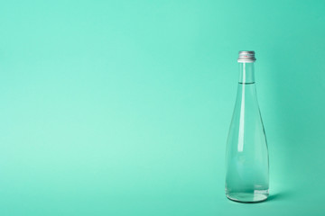 Bottle with water on mint background, space for text