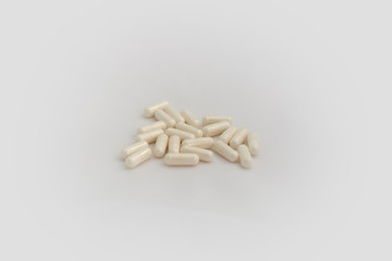 Bunch of pills on white background. Selective focus. Light yellow capsules are scattered over a...