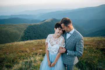 Beautiful european couple embracing in mountains. Outdoor wedding.