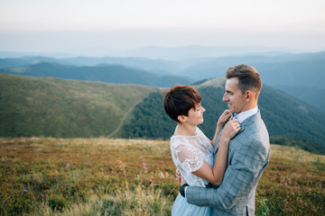 Stylish wedding couple standing in mountais. Outdoor engagement. Mountains wedding inspiration