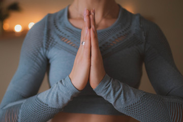 A yoga girl makes Namaste from her hands in a yoga class.