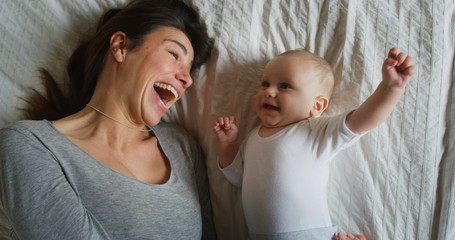 Authentic shot of young happy neo mother is having fun with her newborn baby in a nursery in a...
